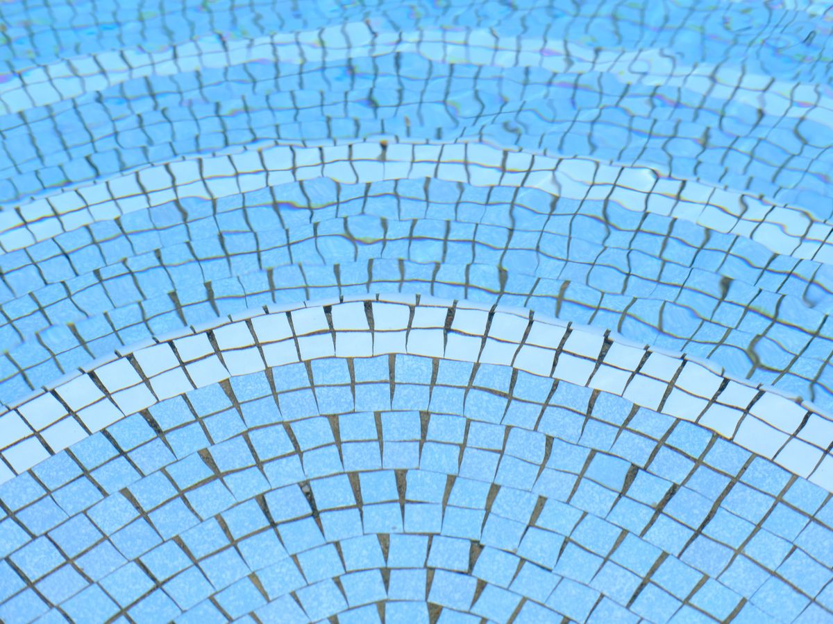 Mosaïque bleue et blanche posée en arcs de cercle au fond d’un bassin